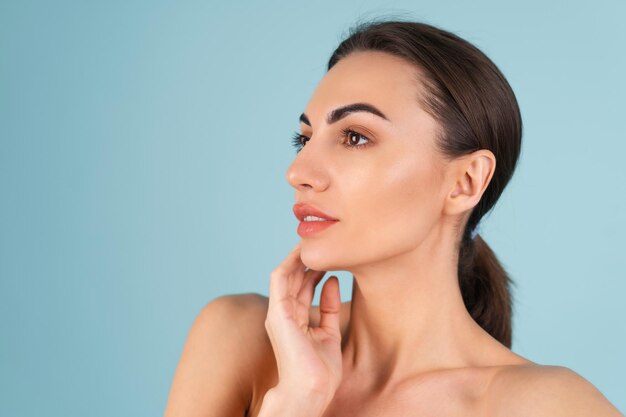 Retrato de belleza cercana de una mujer en topless con piel perfecta y maquillaje natural, labios desnudos regordetes, sobre un fondo azul