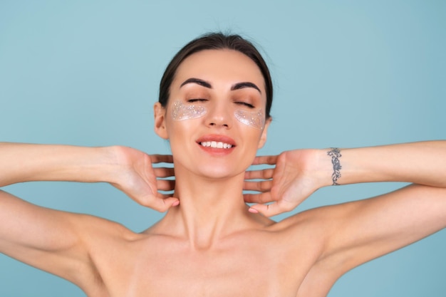 Retrato de belleza cercana de una mujer en topless con piel perfecta y maquillaje natural, parches brillantes debajo de los ojos, para hidratar la piel y aliviar la hinchazón del rostro