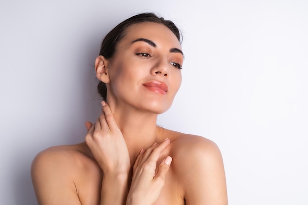 Retrato de belleza cercano de una mujer en topless con piel perfecta y labios desnudos regordetes de maquillaje natural sobre un fondo blancox9