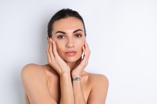 Retrato de belleza cercano de una mujer en topless con piel perfecta y labios desnudos regordetes de maquillaje natural sobre un fondo blancox9