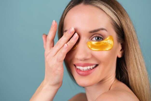 Retrato de belleza cercano de una mujer en topless con piel perfecta y maquillaje natural, parches dorados brillantes debajo de los ojos, para hidratar la piel y aliviar la hinchazón de la cara