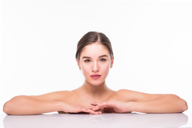 Retrato de belleza de una joven atractiva mujer semidesnuda con piel perfecta posando y mirando a otro lado sobre la pared blanca