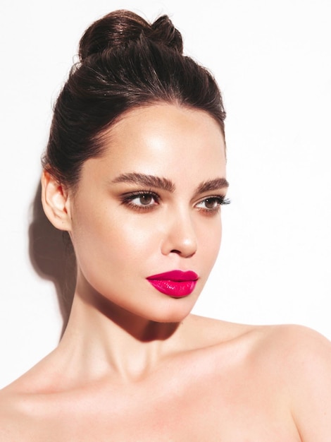 Retrato de belleza de moda de mujer morena joven con maquillaje elegante de noche y piel limpia perfecta Modelo sexy con cabello en un moño posando en estudio Con labios naturales brillantes rosados