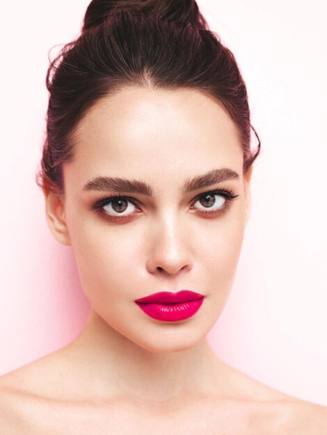 Retrato de belleza de moda de mujer morena joven con maquillaje elegante de noche y piel limpia perfecta Modelo sexy con cabello en un moño posando en estudio Con labios naturales brillantes rosados