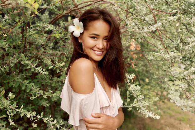 Retrato de la belleza de la muchacha asiática feliz con la cara exótica hermosa que presenta en jardín.