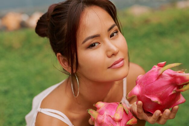 Retrato de la belleza de la mujer asiática bastante joven que sostiene la fruta del dragón pitaya