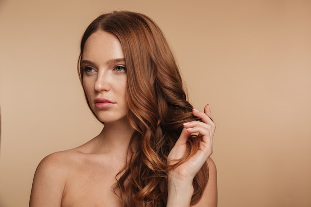 Retrato de belleza de mujer bonita jengibre con cabello largo posando y mirando a otro lado