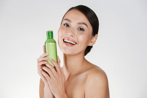 Retrato de belleza de mujer sonriente con piel suave y sana sonriendo y sosteniendo removedor de maquillaje, aislado en blanco