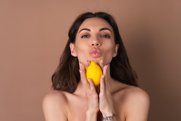 Retrato de belleza de mujer en topless con piel perfecta y maquillaje natural sobre un fondo beige contiene vitaminas c de limón cítrico para la piel