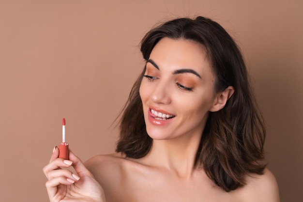 Retrato de belleza de mujer en topless con piel perfecta y maquillaje natural sobre fondo beige con lápiz labial marrón chocolate brillante