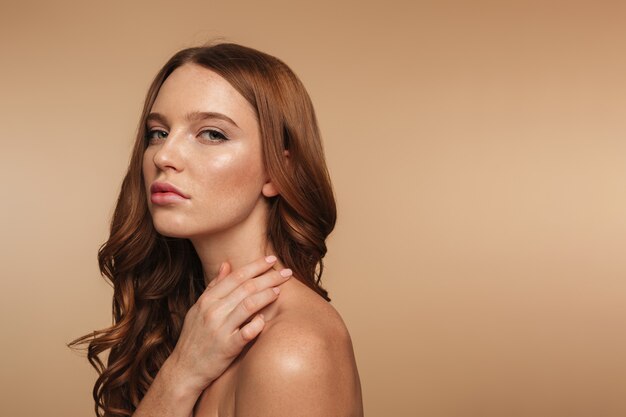 Retrato de la belleza de la mujer tranquila de jengibre con el pelo largo posando de lado y mirando