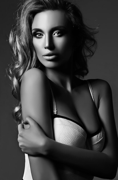 Retrato en blanco y negro de glamour sensual hermosa mujer rubia modelo dama con maquillaje fresco y cabello rizado saludable