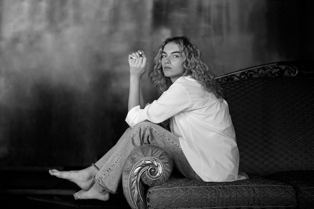 Retrato en blanco y negro de una mujer hermosa posando en el interior de un sofá