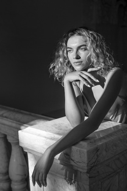 Retrato en blanco y negro de una mujer hermosa posando en el interior con un vestido