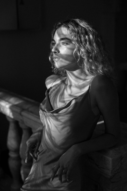 Retrato en blanco y negro de una mujer hermosa posando en el interior con un vestido