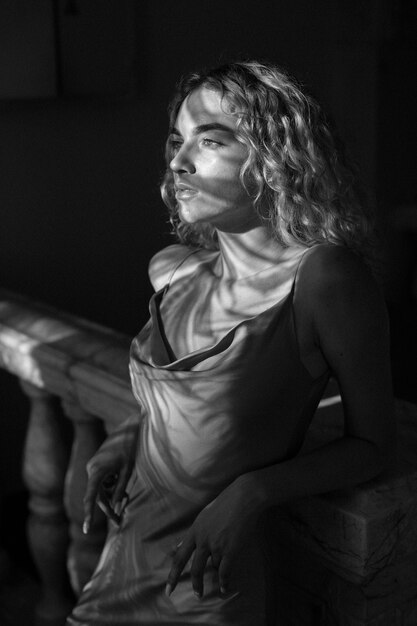 Retrato en blanco y negro de una mujer hermosa posando en el interior con un vestido