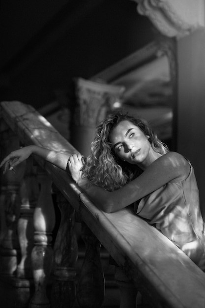 Retrato en blanco y negro de una mujer hermosa posando en el interior con un vestido