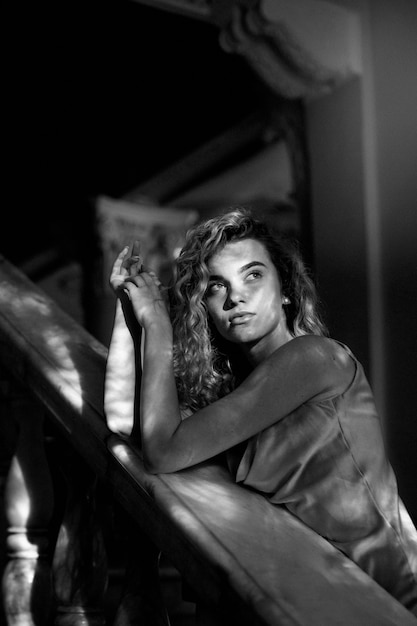 Retrato en blanco y negro de una mujer hermosa posando en el interior con un vestido