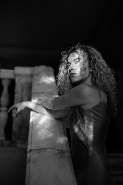 Retrato en blanco y negro de una mujer hermosa posando en el interior con un vestido