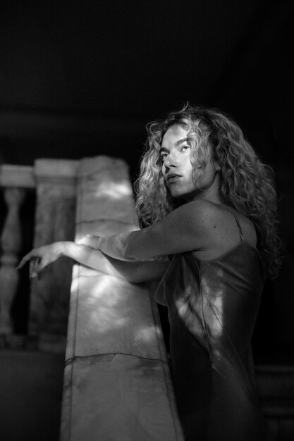 Retrato en blanco y negro de una mujer hermosa posando en el interior con un vestido