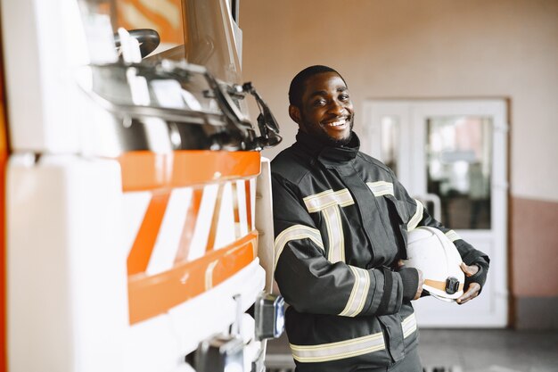 Retrato de un bombero de pie delante de un camión de bomberos