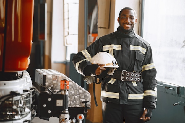 Foto gratuita retrato de un bombero de pie delante de un camión de bomberos