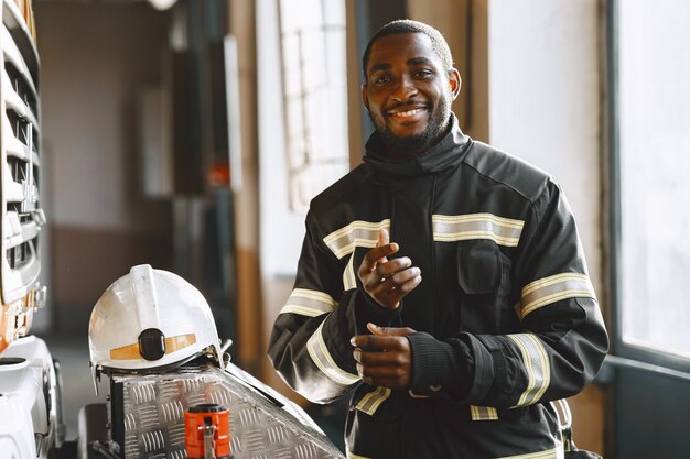 Retrato de un bombero de pie delante de un camión de bomberos