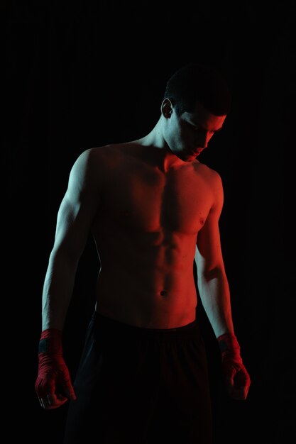 Retrato de boxeador masculino posando en luz roja y blanca