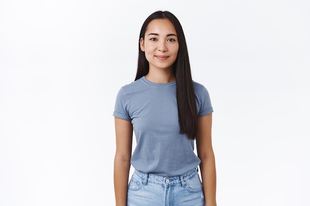 Retrato de buena apariencia sonriente joven estudiante asiática se fue al extranjero a estudiar y ver el mundo, sonriendo alegremente, de pie en una pose relajada casual y expresando positividad