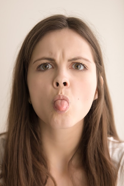 Foto gratuita retrato en la cabeza de mujer enojada mostrando lengua