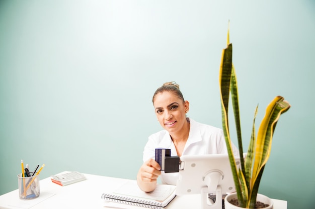 Foto gratuita retrato de una cajera en una recepción de negocios deslizando una tarjeta de crédito en un lector y sonriendo