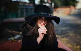 Foto gratuita retrato de la calle de la joven dama casual con sombrero, ropa negra, labios rojos