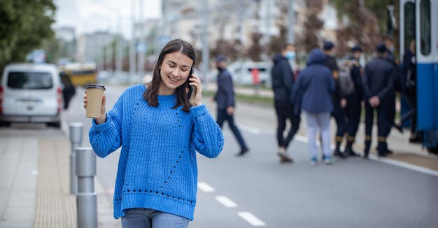 Retrato de la calle de una mujer joven hablando por teléfono en la ciudad cerca de la carretera