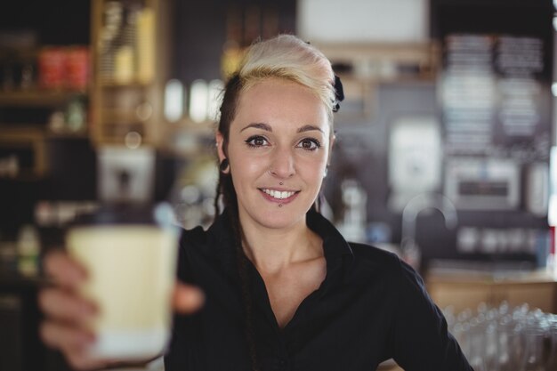 Retrato de camarera de pie con una taza de café desechable