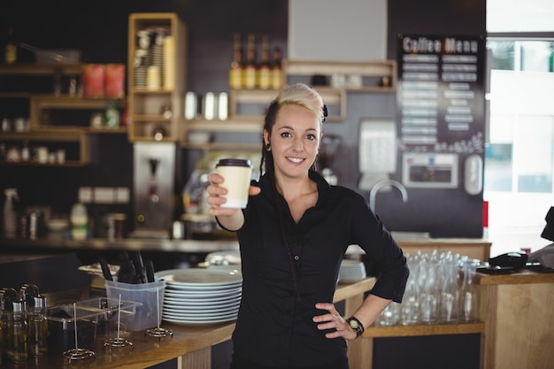 Retrato de camarera de pie con una taza de café desechable
