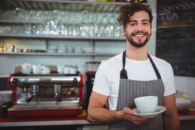 Retrato de camarero que sostiene una taza de café