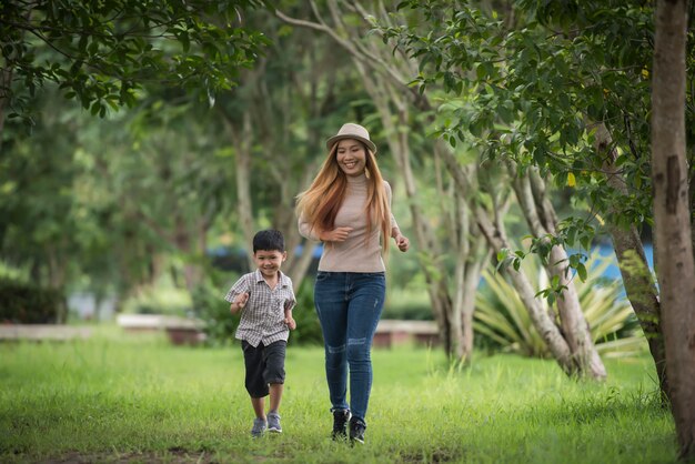 Retrato de caminar feliz de la madre y del hijo junto en el parque que lleva a cabo la mano.