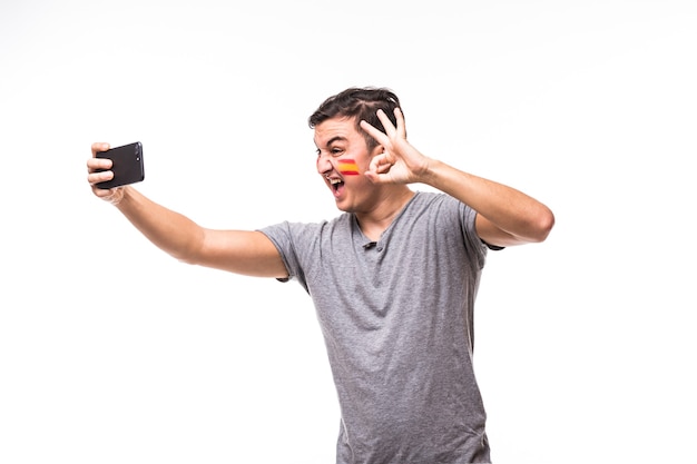 Retrato de la cara del aficionado al fútbol de España tomar selfie sobre fondo blanco. Concepto de aficionados al fútbol.