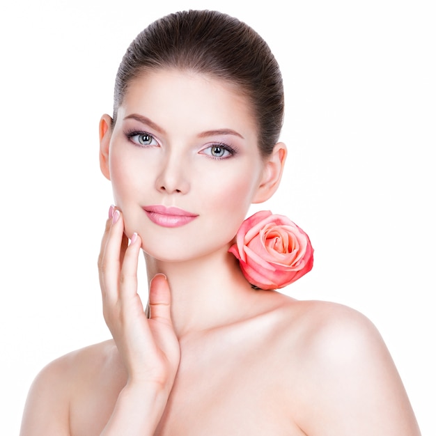 Retrato de cara bonita de mujer hermosa con una rosa rosa - aislada en blanco.