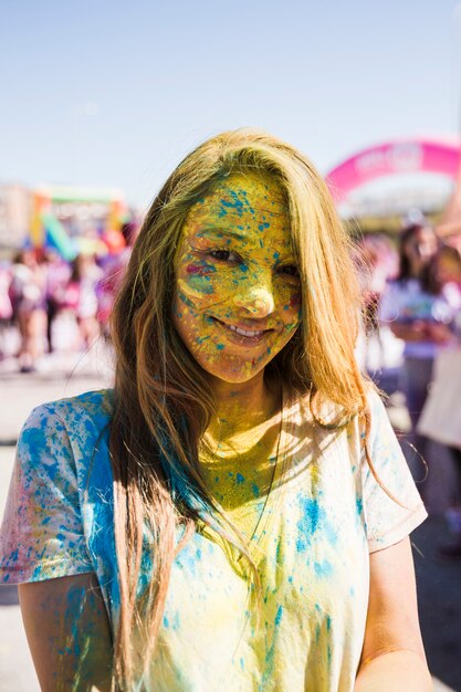 Retrato de la cara de una mujer joven cubierta con holi en polvo mirando a la cámara