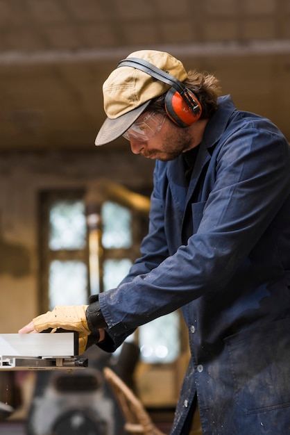 Retrato de un carpintero hombre con oreja defensor trabajando en taller