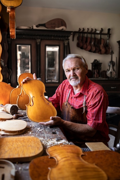 Retrato de carpintero senior en su antiguo taller haciendo violines instrumento musical para la academia de artes