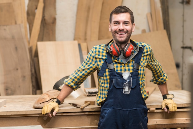 Foto gratuita retrato de un carpintero de sexo masculino que se coloca delante del banco de trabajo