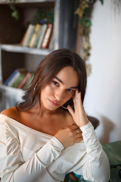 Retrato de cerca de una adorable joven llevándose la mano a la cabeza y mirando a la cámara Foto de alta calidad