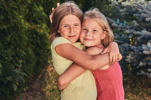 Retrato de cerca de dos amigas felices abrazándose en el parque.