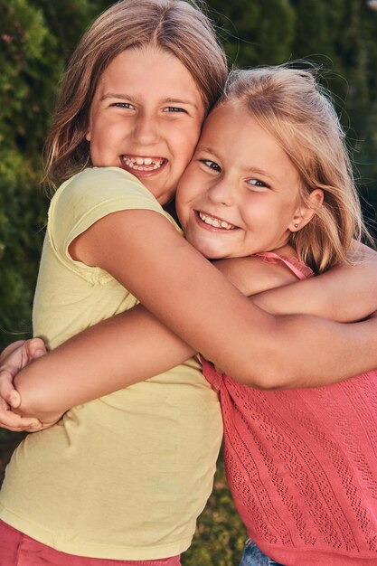 Retrato de cerca de dos amigas felices abrazándose en el parque.