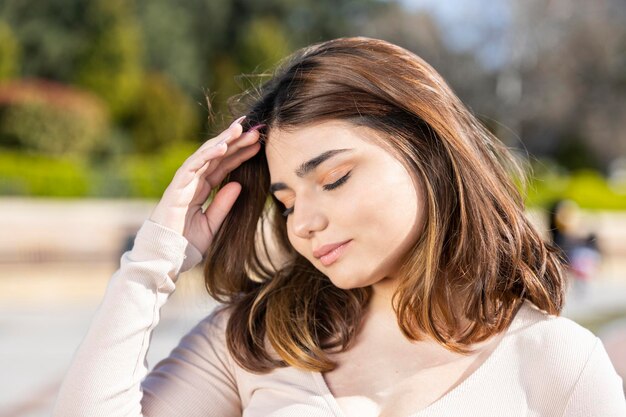 Retrato de cerca de una joven hermosa que cierra los ojos y le da forma al cabello Foto de alta calidad