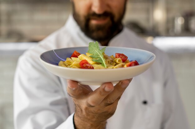 Retrato de un chef masculino en la cocina sosteniendo un plato de comida