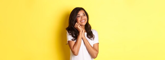 Foto gratuita retrato de una chica afroamericana soñadora y hermosa que mira con admiración la esquina superior izquierda a