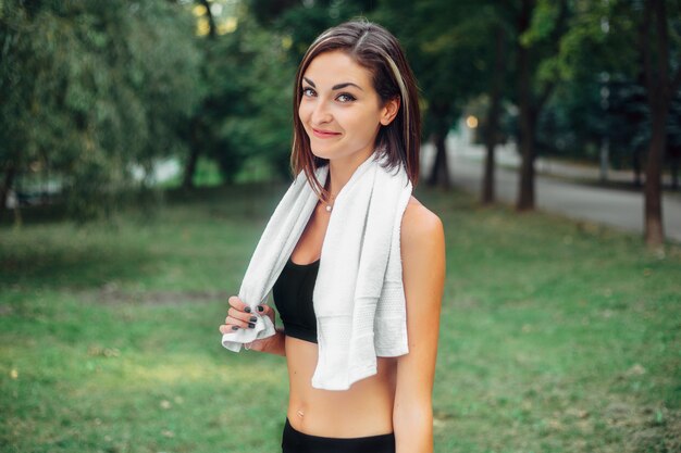 Retrato de una chica atlética. Modelo de fitness deporte joven hermosa preparándose para correr en el parque de la ciudad.